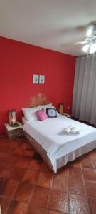 a bedroom with a large bed with a red wall at Hospedagem Vista Real in Casa Branca