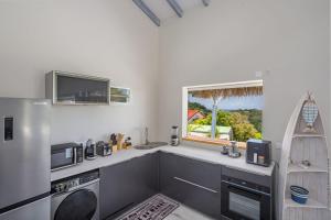 a kitchen with a refrigerator and a sink and a window at La Villa de Solange - Azur in La Trinité