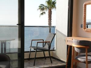 a room with a chair and a table and a palm tree at Ciftlique Otel Cesme in Çeşme