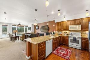 a large kitchen with wooden cabinets and a living room at Salmon Run Condo - Overlooking the Spokane River in Post Falls +20 photos