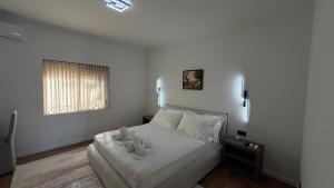 a white bedroom with a bed and a window at Solemar4 in Vlorë