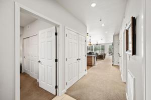 a white hallway with white doors and a kitchen at Riverside Condo - Gorgeous Spokane River View in Post Falls