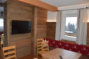 sala de estar con paredes de madera y TV de pantalla plana. en Ferienhaus Enterberg, en Ramsau im Zillertal