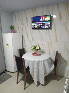 a white table with chairs and a tv on a wall at Aluguel casa azul in Capão da Canoa