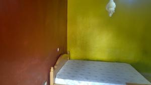 a small bed in a room with a yellow wall at Madina Homes in Butare