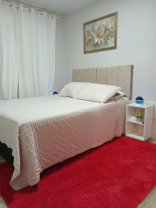 a bedroom with a white bed with a red rug at Aluguel casa azul in Capão da Canoa