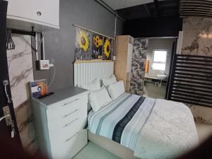 a bedroom with a white bed with a dresser and a window at Gaia Hydro-Spa and Guest House in Cape Town