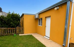 a yellow house with a white door in a yard at Departamento norte interno in Rafaela