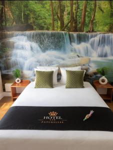 a bed in a room with a waterfall mural at Hôtel les Paturelles in Avesnelles