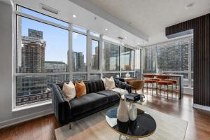a living room with a black couch and large windows at NoMad Suites - Toronto's Entertainment District in Toronto +51 photos