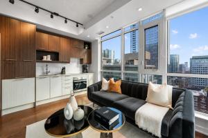 a living room with a black couch and a large window at NoMad Suites - Toronto's Entertainment District in Toronto