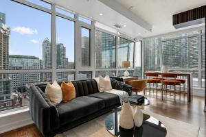 a living room with a black couch and large windows at NoMad Suites - Toronto's Entertainment District in Toronto