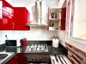 a kitchen with red cabinets and a stove top oven at close to beach and 15 mints to la rambla by tren in Sant Adria de Besos +24 photos