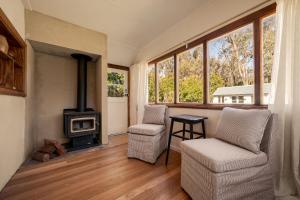 a living room with two chairs and a wood stove at Harvest Cottage Blue Mountains in Leura