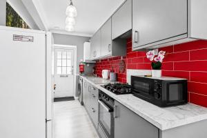 a kitchen with white cabinets and red tiles at Spacious two bedroom flat in Lansdowne in Bournemouth +3 photos