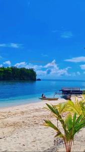 a beach with two people in a boat on the water at Togean Pulotiga Resort in Popolii