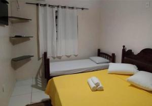 two beds in a room with yellow sheets and towels at Trindade Flat Azulmar in Trindade