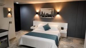 a bedroom with a large white bed with a blue blanket at Hotel Casa Esmeralda in Cali