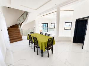 a dining room with a green table and chairs at villa face à la mer in Cotonou