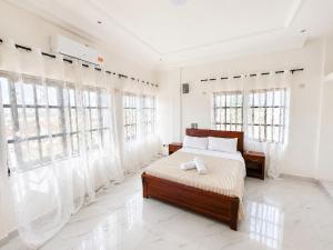 a bedroom with a bed with white walls and windows at villa face à la mer in Cotonou +8 photos