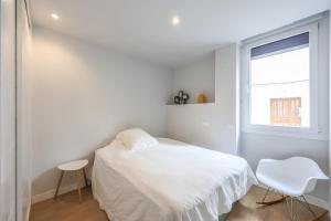 a white bedroom with a bed and a window at Spacious Home with Private Garden and Parking in Madrid
