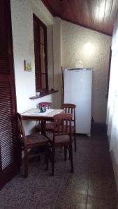 a kitchen with a table and chairs and a refrigerator at Flat - Condomínio Summerville Apart in Miguel Pereira