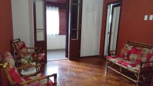 a living room with two chairs and a door at Flat - Condomínio Summerville Apart in Miguel Pereira
