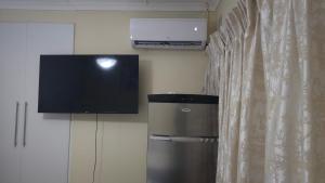 a flat screen tv on a wall next to a curtain at 3D Power guest house in Durban