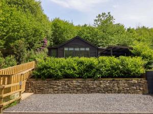 a garden with a stone retaining wall and a house at Lodge at Nadur in Machynlleth