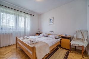 a bedroom with a bed and a chair and a window at Apartments Cvelic Milovcic in Malinska