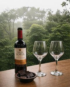 a bottle of wine and two wine glasses on a table at MindoLoft Loft de lujo con servicio premium en Mindo in Mindo