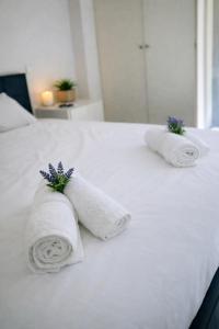 two rolled towels on a white bed with purple flowers at Corinth Central Studio in Korinthos