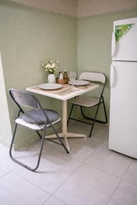 a table and chairs in a kitchen with a white refrigerator at Corinth Central Studio in Korinthos