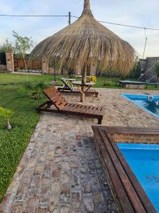 a picnic table with a straw umbrella next to a pool at Don Vito Casa de Huespedes in Cucullú