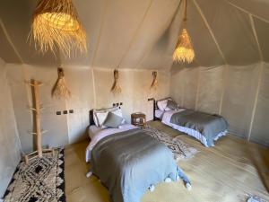 a room with two beds in a tent at Merzouga Luxury Camping in Merzouga