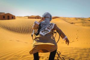 a woman in the desert talking on a cell phone at Merzouga Luxury Camping in Merzouga +17 photos