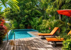 a swimming pool with two chairs and an umbrella at Casa Mapache Pool and Breakfast Available near Tamarindo Beach in Tamarindo