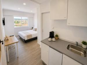 a kitchen with a sink and a bed in a room at Exclusive Studio Kitchenette e WC Privativo in Abrantes