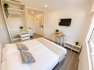 a bedroom with a large white bed and a television at Exclusive Studio Kitchenette e WC Privativo in Abrantes