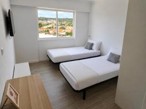 two beds in a small room with a window at Exclusive Studio Kitchenette e WC Privativo in Abrantes