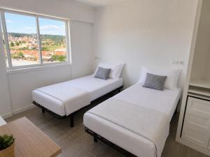 two beds in a room with a window at Exclusive Studio Kitchenette e WC Privativo in Abrantes