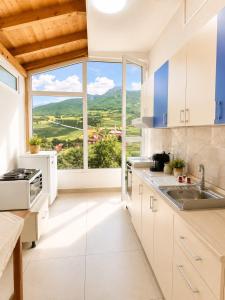a kitchen with white cabinets and a large window at Amarildo Rooms in Durrës