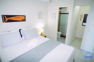 a white bedroom with a white bed and a bathroom at Praia Studios in Vila Velha +33 photos