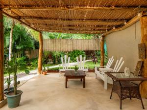 a patio with white chairs and a wooden pergola at Casa Mapache Pool and Breakfast Available near Tamarindo Beach in Tamarindo