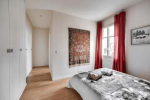 a bedroom with a bed and a window with red curtains at 100 m terrace parking view of the Eiffel Tower in Saint-Cloud