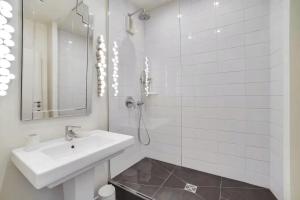 a white bathroom with a sink and a mirror at 100 m terrace parking view of the Eiffel Tower in Saint-Cloud +5 photos