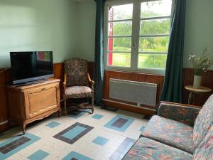 a living room with a tv and a chair at Maison Le Merle Rouge in Sazeray
