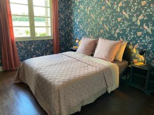 a bedroom with a bed with a floral wallpaper at Maison Le Merle Rouge in Sazeray
