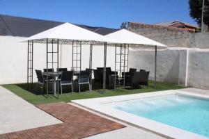 a table and chairs under a white umbrella next to a pool at Can Guzmu in Cijuela