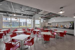 a restaurant with white tables and red chairs at City Express Junior by Marriott Ciudad de México Zona Reforma in Mexico City